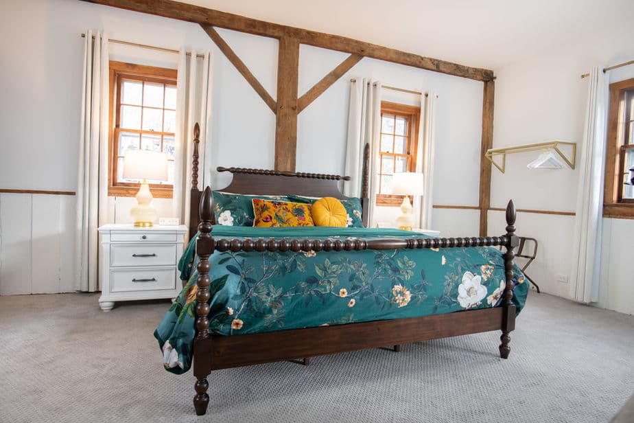 An inviting bedroom with king four-poster bed, white walls, and natural wood accents.