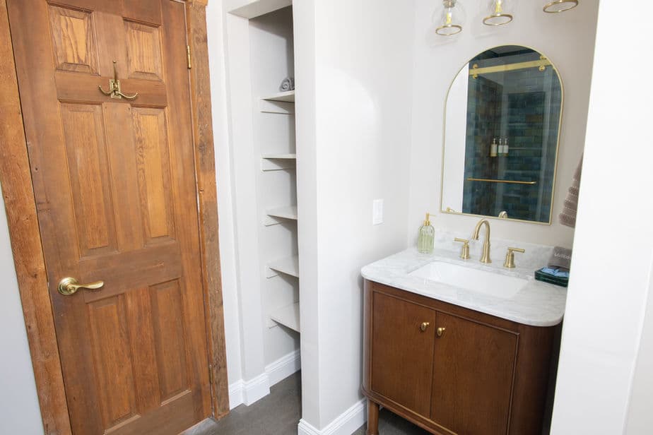 Bathroom with built-in shelves for linens, a vanity sink, and a mirror reflecting the shower.