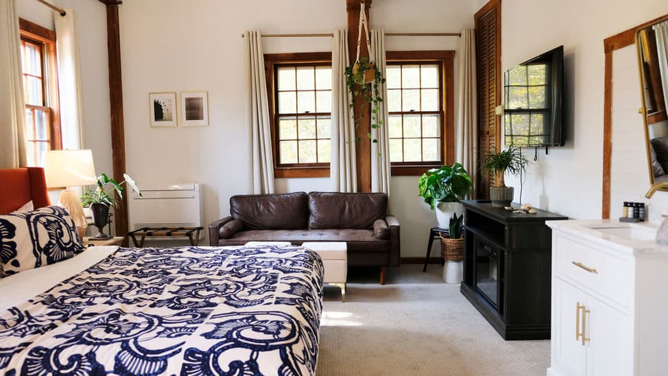 Spacious bedroom with king bed, loveseat, sink, and wall-mounted smart TV.