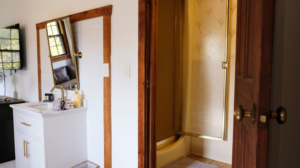 An open door leads from the bedroom to the bathroom with shower and toilet. The sink is located in the bedroom.