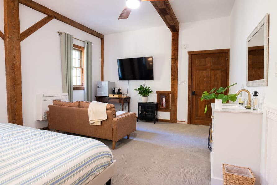 Bedroom with king bed, sink, loveseat, and wall-mounted smart TV.