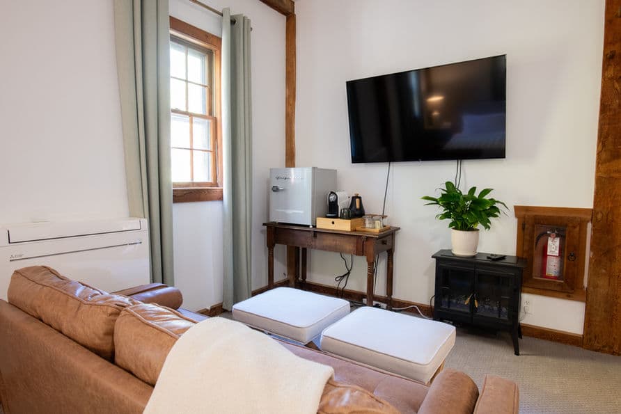 Cozy sitting area with loveseat, ottoman, coffee bar, and smart TV.