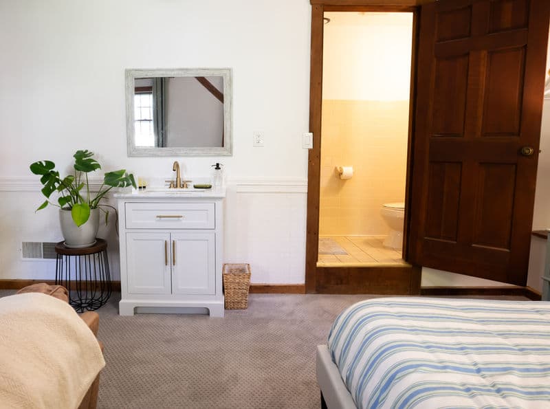 Open doorway leading from bedroom to bathroom with toilet & shower. The sink is in the bedroom.