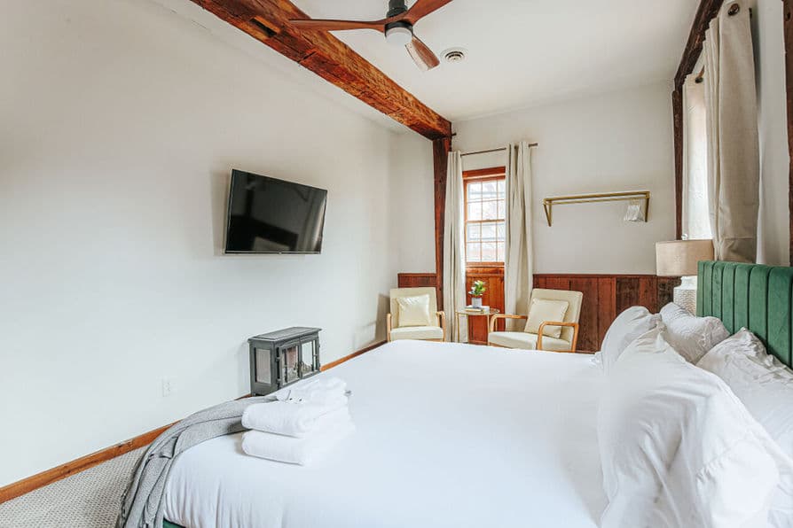 King-size bed with painted wooden headboard and lofty white bedding and pillows.
