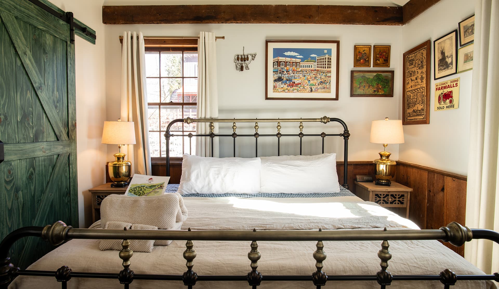 Cozy bedroom featuring a vintage bed, warm lighting, and decorated walls with art and a green sliding barn door.