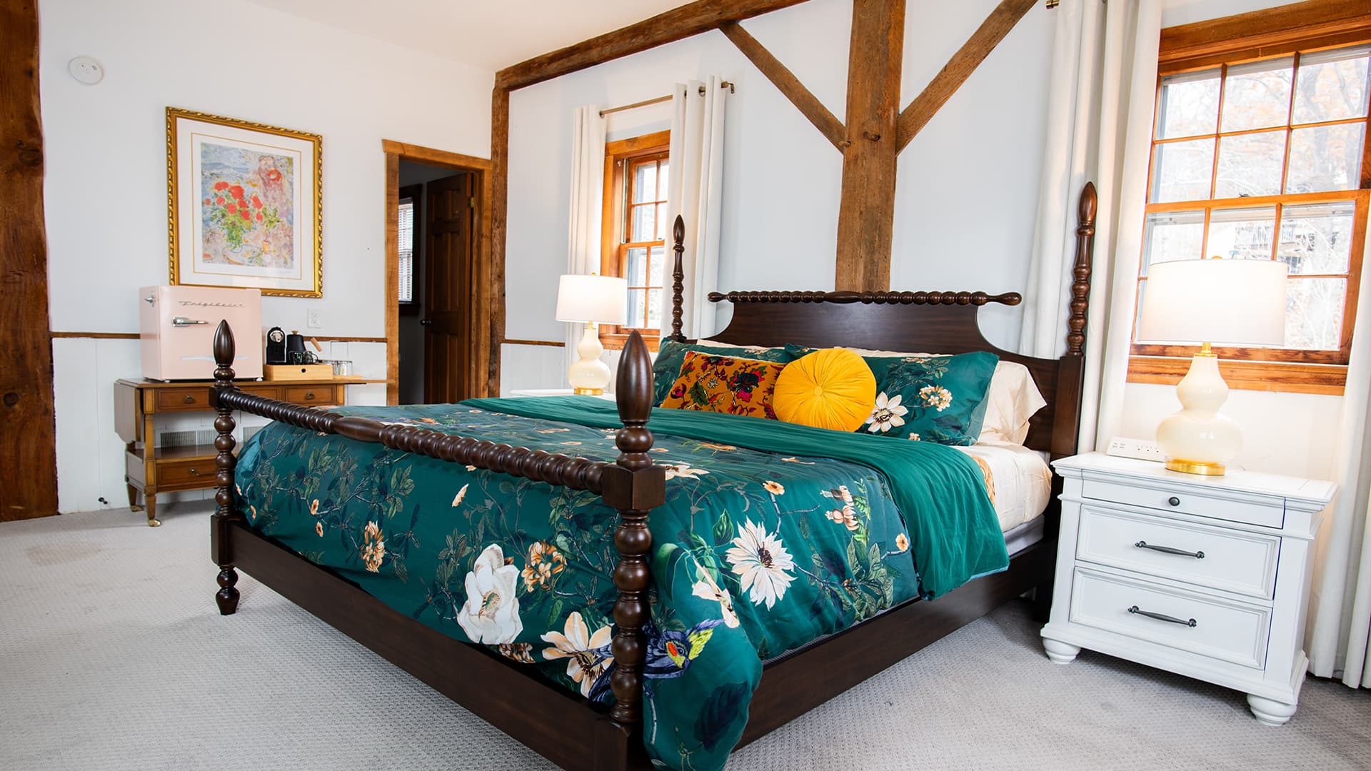 Cozy bedroom featuring a dark wood bed, floral bedding, and warm lighting.